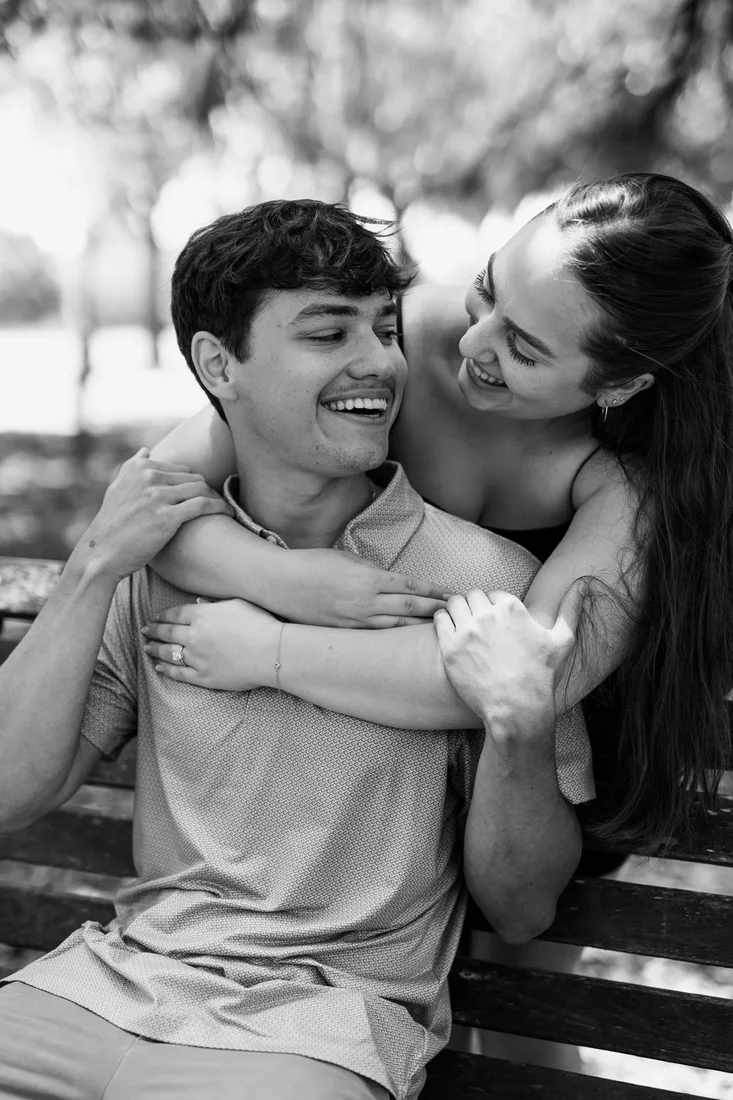 Young couple embracing on a park bench, black and white