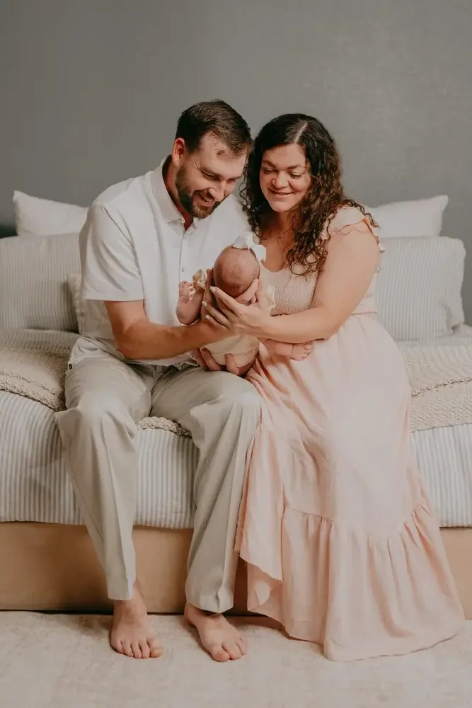 New parents smiling down at their newborn on the bed