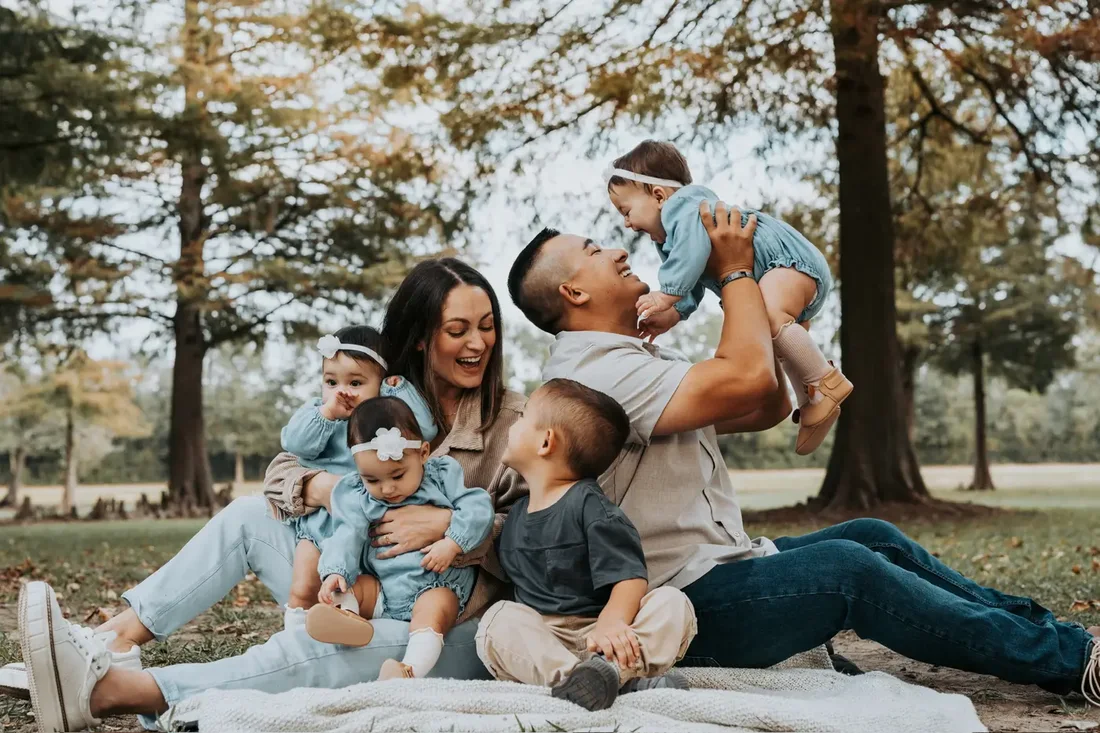 Family of six with young quadruplets on a picnic blanket