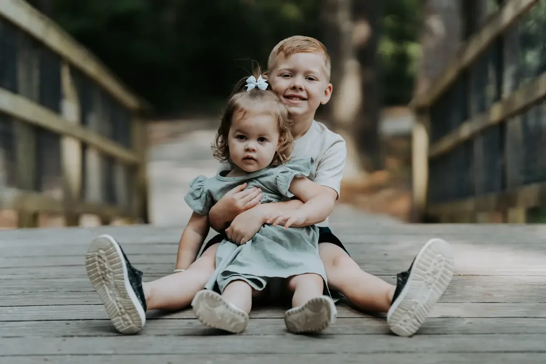 Brother and sister sitting together on a bridge