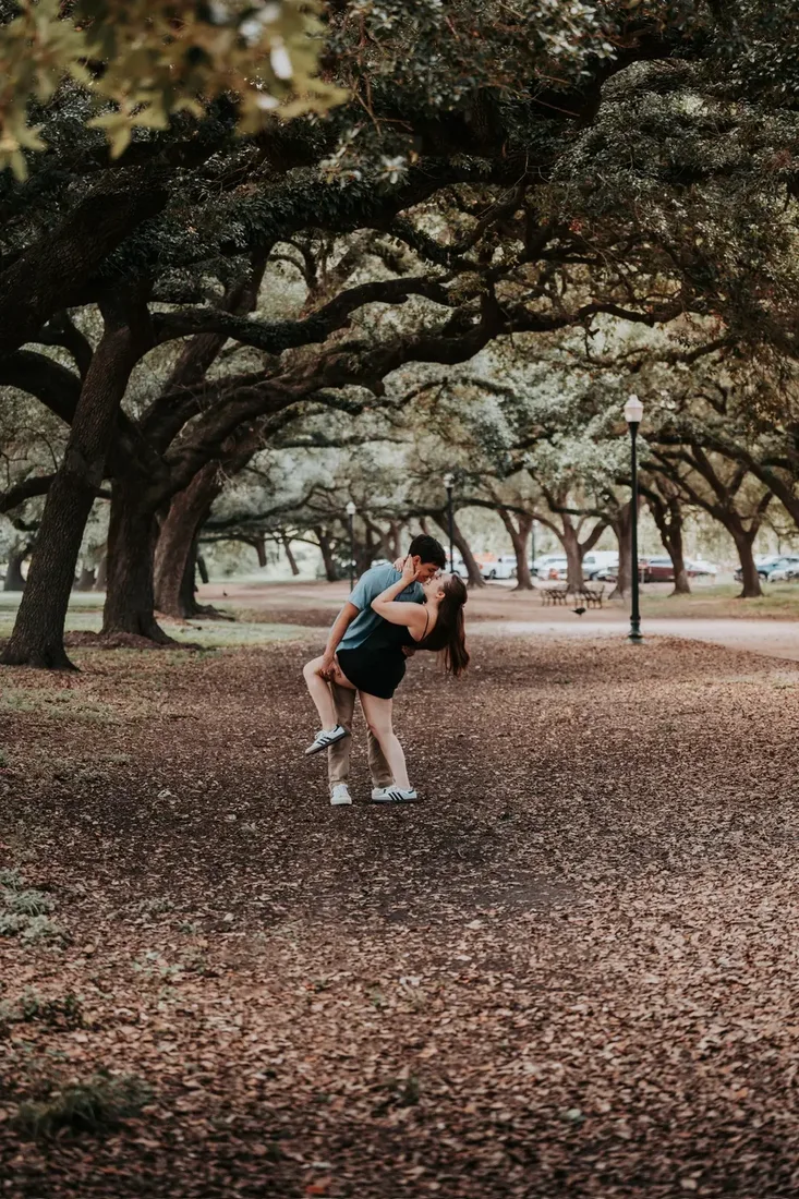 Engagement session, couple sharing a kiss on a tree-lined path