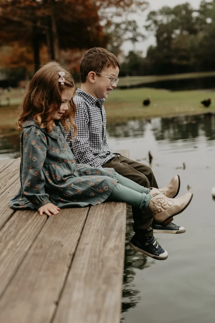 Brother and sister sitting on a dock by the water