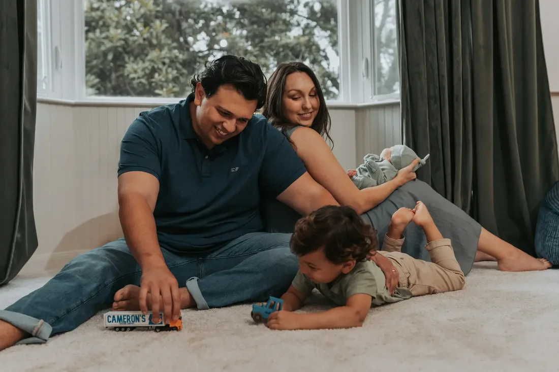 Newborn getting kisses from mom and dad on the floor